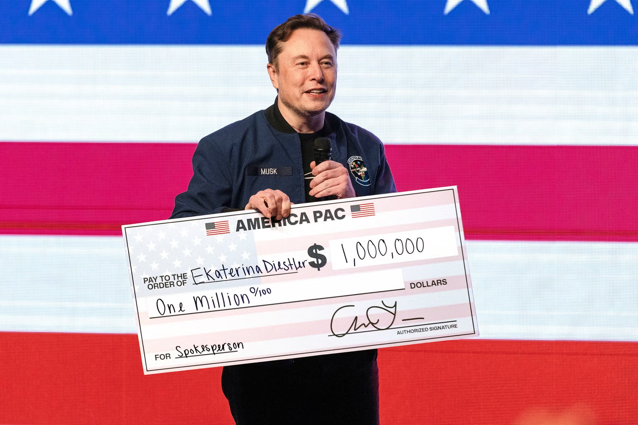 Elon Musk holding a large America PAC presentation check