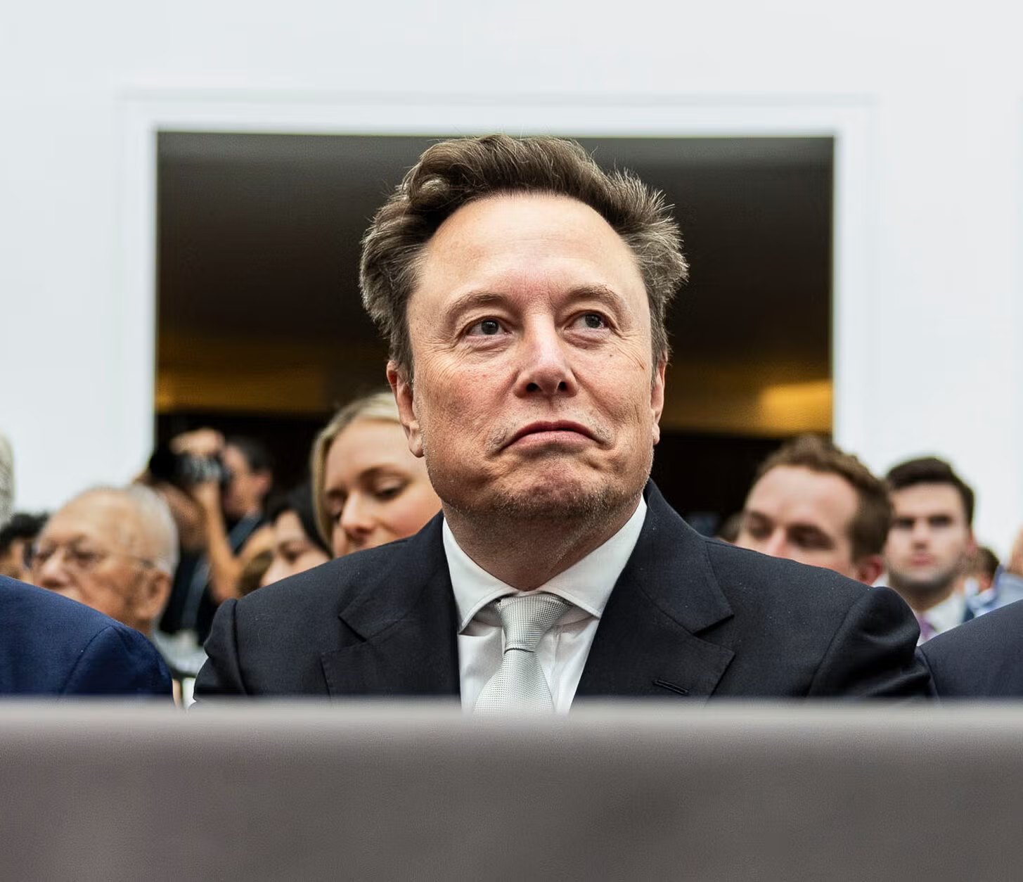 Elon Musk seated in a suit